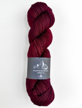 Burgundy skein of yarn with a label on a white background