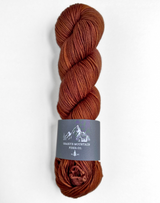 Brown skein of yarn with a label on a white background