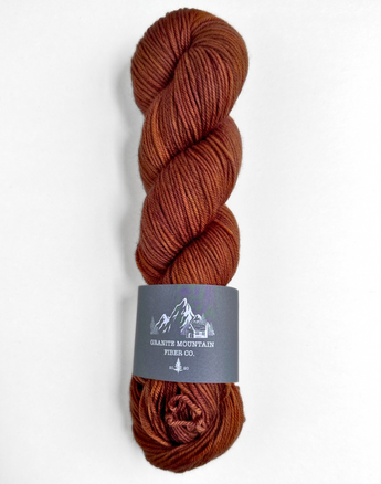 Brown skein of yarn with a label on a white background
