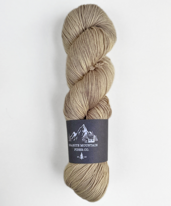 Beige skein of yarn with a label on a white background