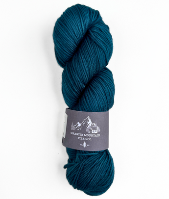 Teal skein of yarn with a label on a white background