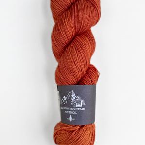 B urnt orange skein of yarn with a label on a white background