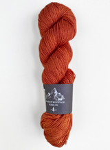 B urnt orange skein of yarn with a label on a white background
