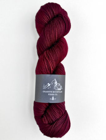 Burgundy skein of yarn with a label on a white background