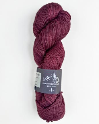 Burgundy skein of yarn with a label on a white background