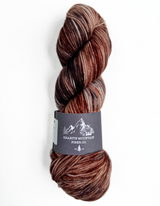 Brown skein of yarn with a label on a white background