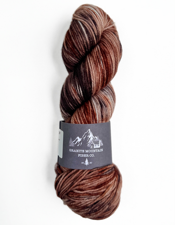Brown skein of yarn with a label on a white background