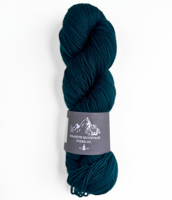 Teal skein of yarn with a label on a white background